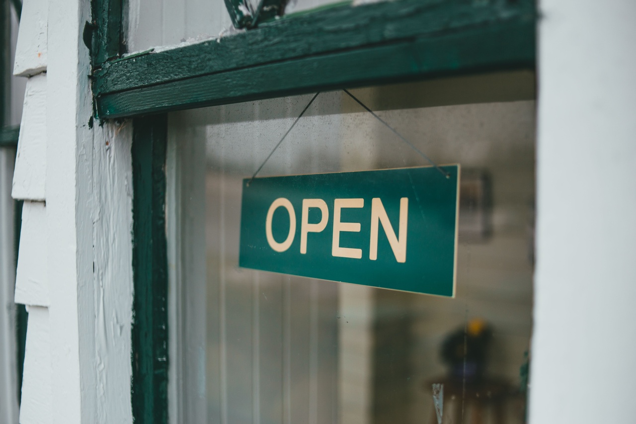 店舗のドアに掛けられた緑色のOPENの看板